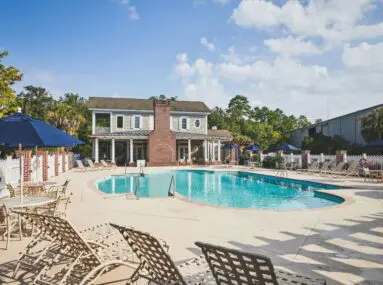 pool with chairs around it and a house in the background