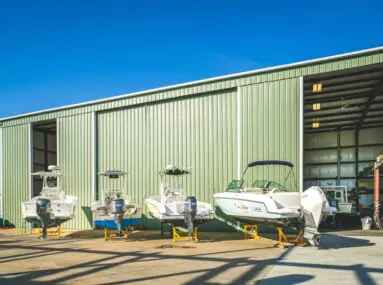4 boats sitting on raised platforms outside a hanger