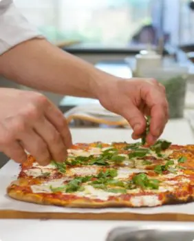 hands assembling pizza