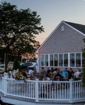 outdoor dining patio with string lights and people eating at tables