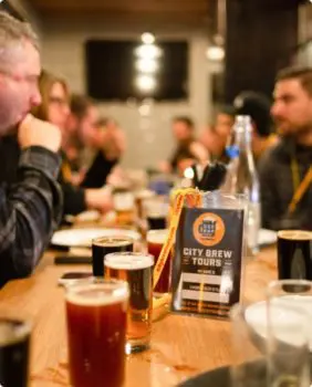 people sitting at tables with a sign that says city brew tours