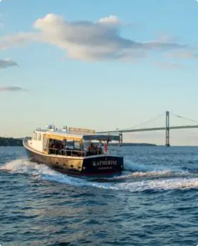 boat that says katherine on the back cruising with a bridge in the background