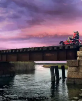 two people riding in a two person bike on a railway at sunset