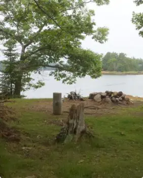 grass and fire pit with body of water in the background