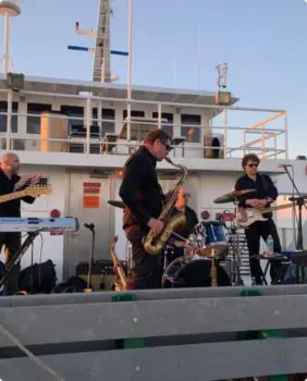 man playing saxophone with band behind him