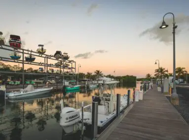 fishing boats docked with boats in storage in the background at sunset