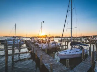 sailboats and fishing boats docked at sunset