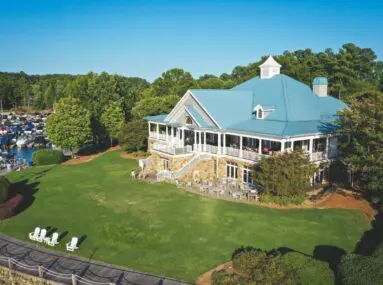 Building with blue roof and patio seating with a large lawn in front