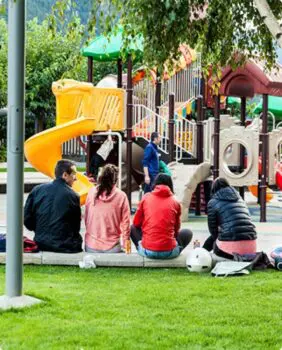 4 parents watching their children play on a playground