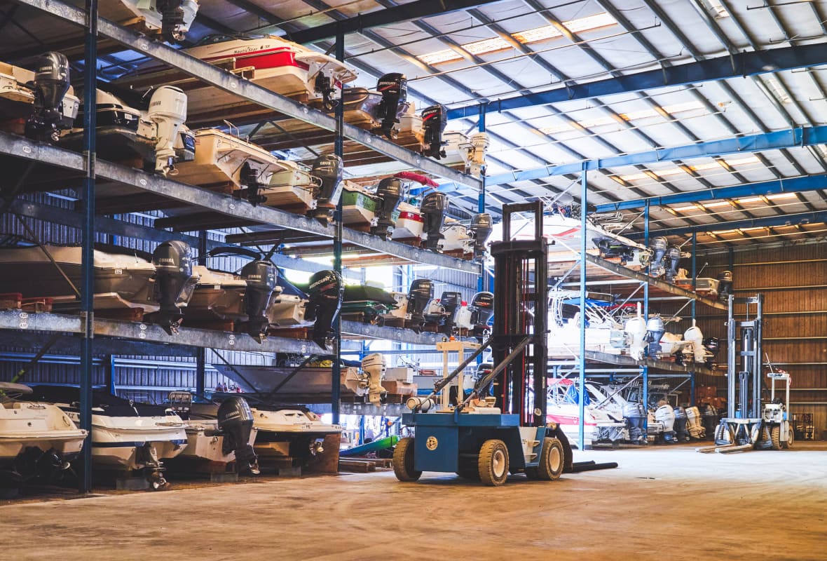 many boats on racks being stored in a warehouse