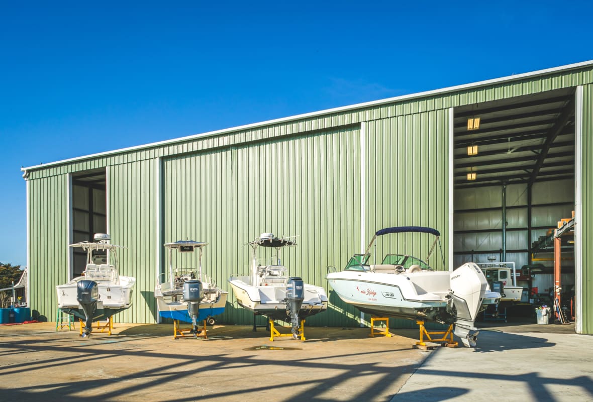 4 boats sitting on raised platforms outside a hanger