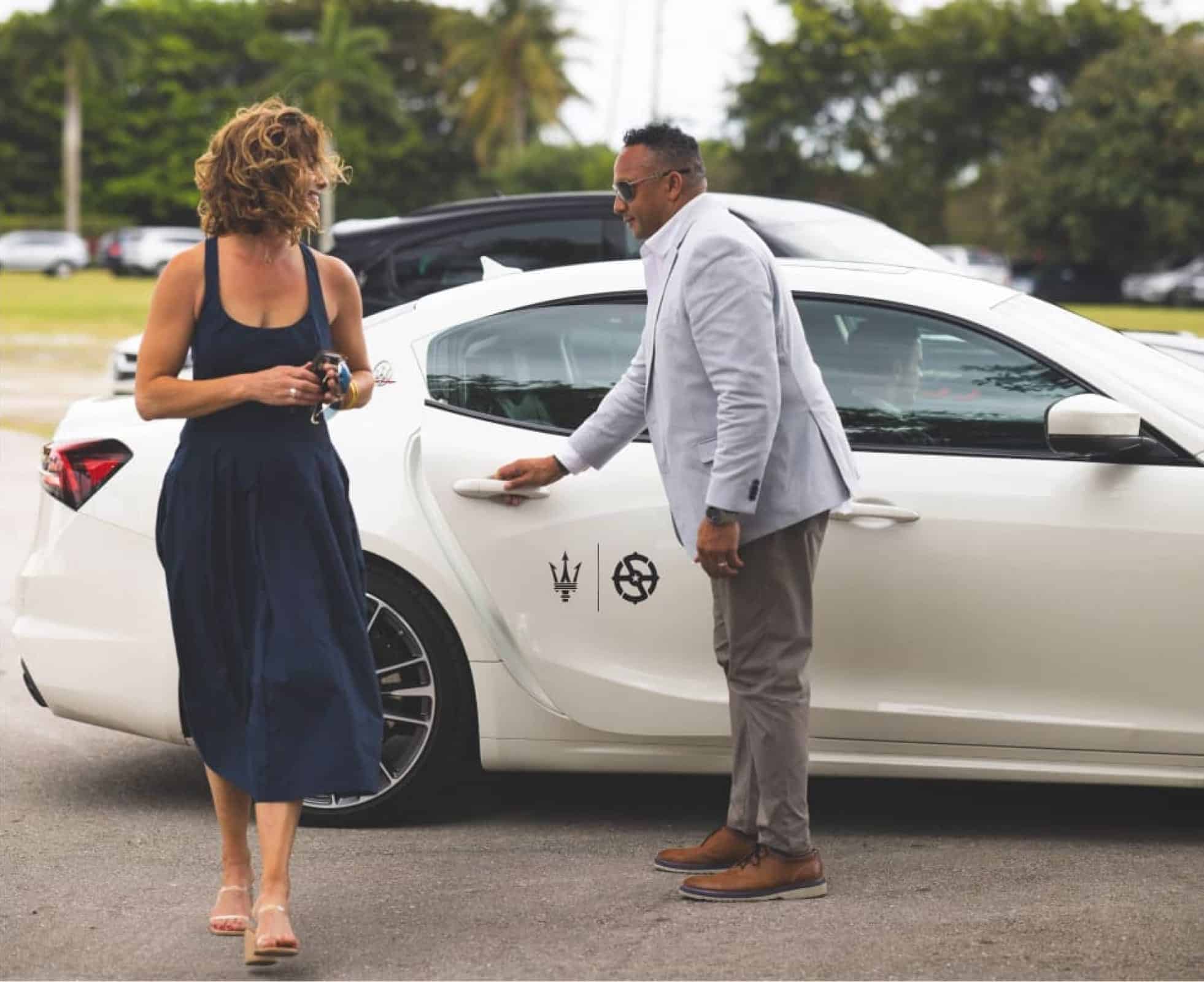 man and woman stand outside a maserati with Safe Harbor helm logo on the side