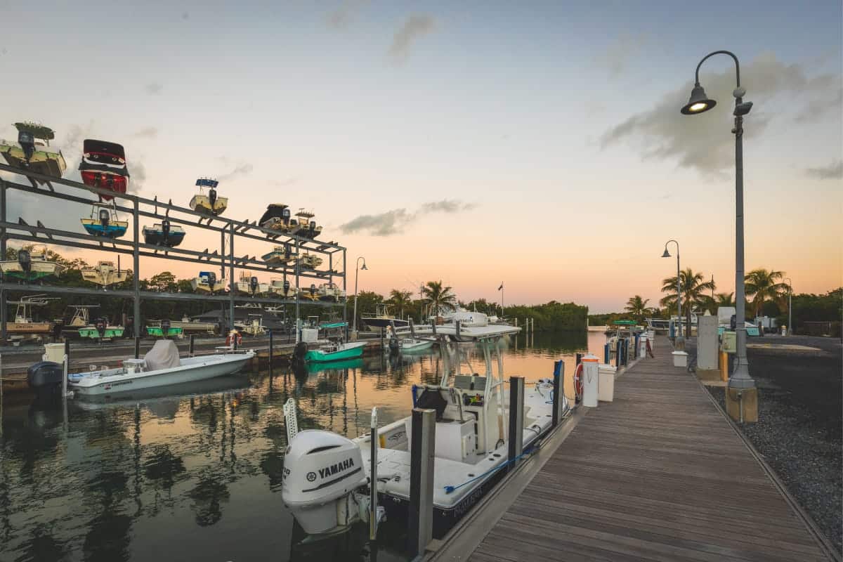 fishing boats docked with boats in storage in the background at sunset
