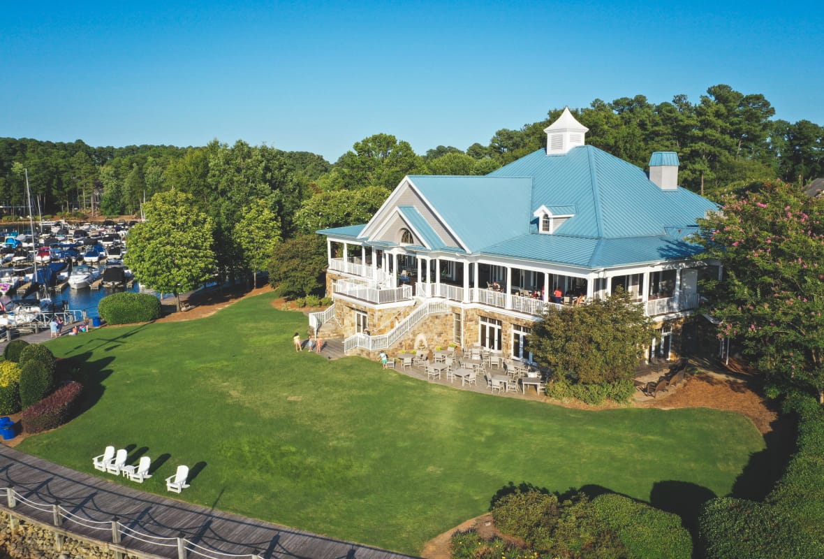 Building with blue roof and patio seating with a large lawn in front