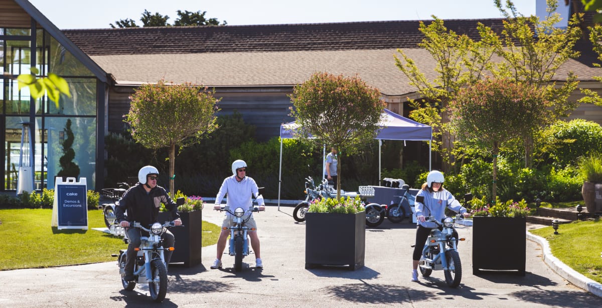 three people riding small motorcycles with helmets on