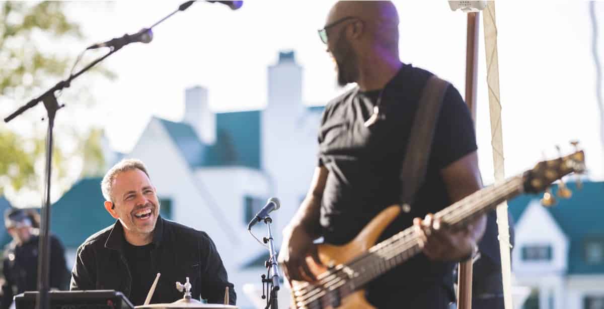 man smiling playing the drums