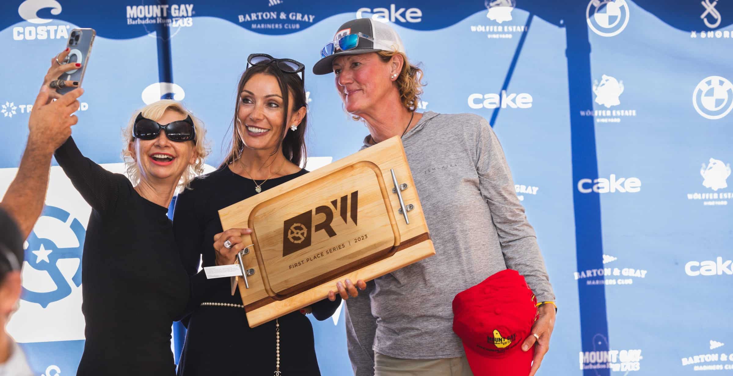 three women take selfie with first place board